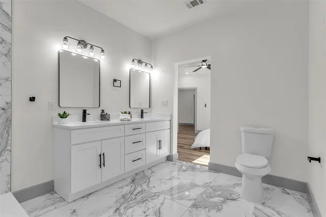 a bathroom with a double vanity sink mirror and toilet
