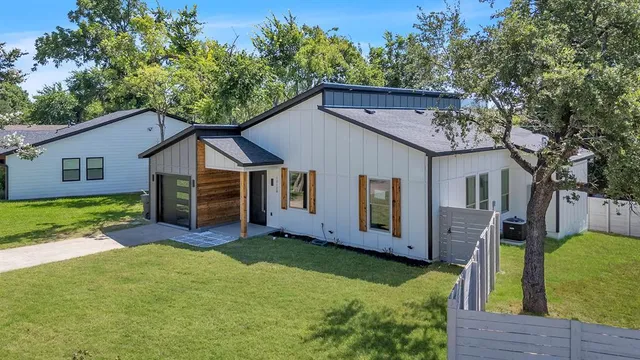 a view of a house with a big yard plants and large tree
