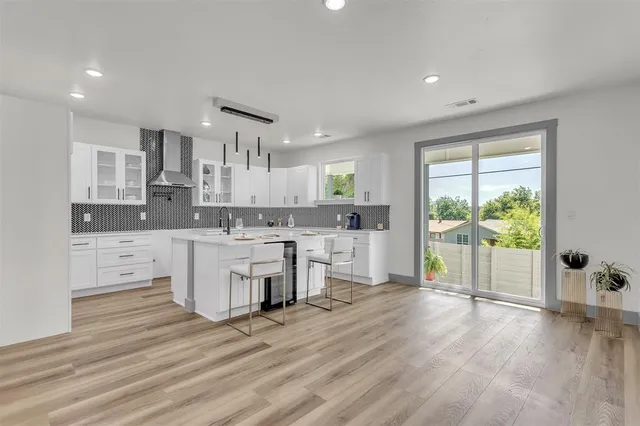 a large kitchen with kitchen island a stove a refrigerator a sink dishwasher with a dining table and chairs with wooden floor