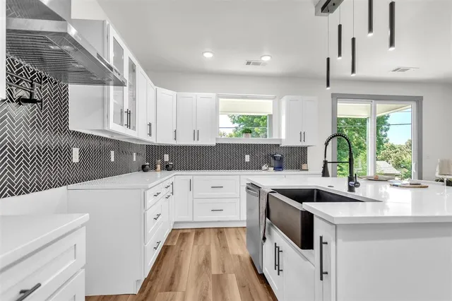 a kitchen with white cabinets appliances and a window