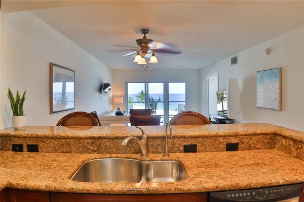 a view of a kitchen with granite countertop a sink a window and dining table