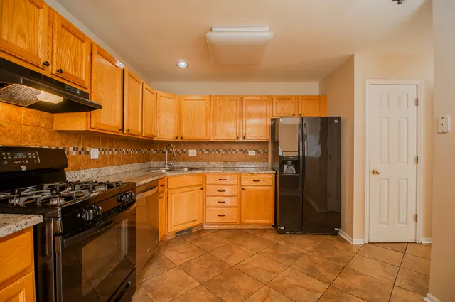 a kitchen with stainless steel appliances granite countertop a refrigerator stove and sink