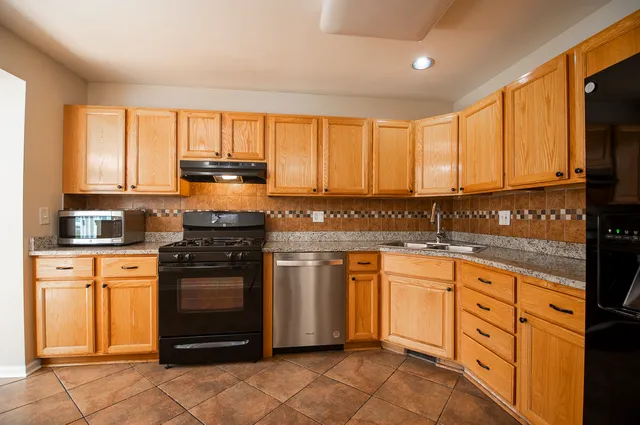 a kitchen with granite countertop white cabinets sink and stainless steel appliances