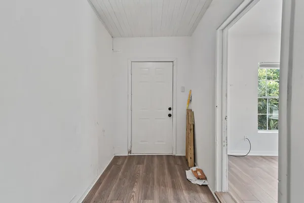 an empty room with wooden floor chandelier fan and windows