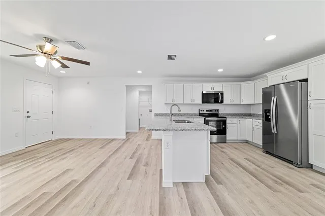 a view of kitchen with stainless steel appliances granite countertop a stove top oven a sink and a refrigerator
