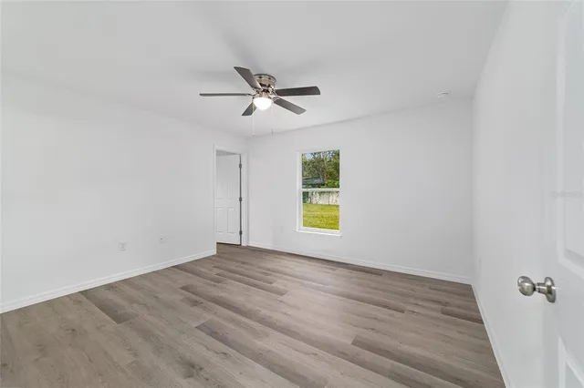 an empty room with wooden floor and a ceiling fan