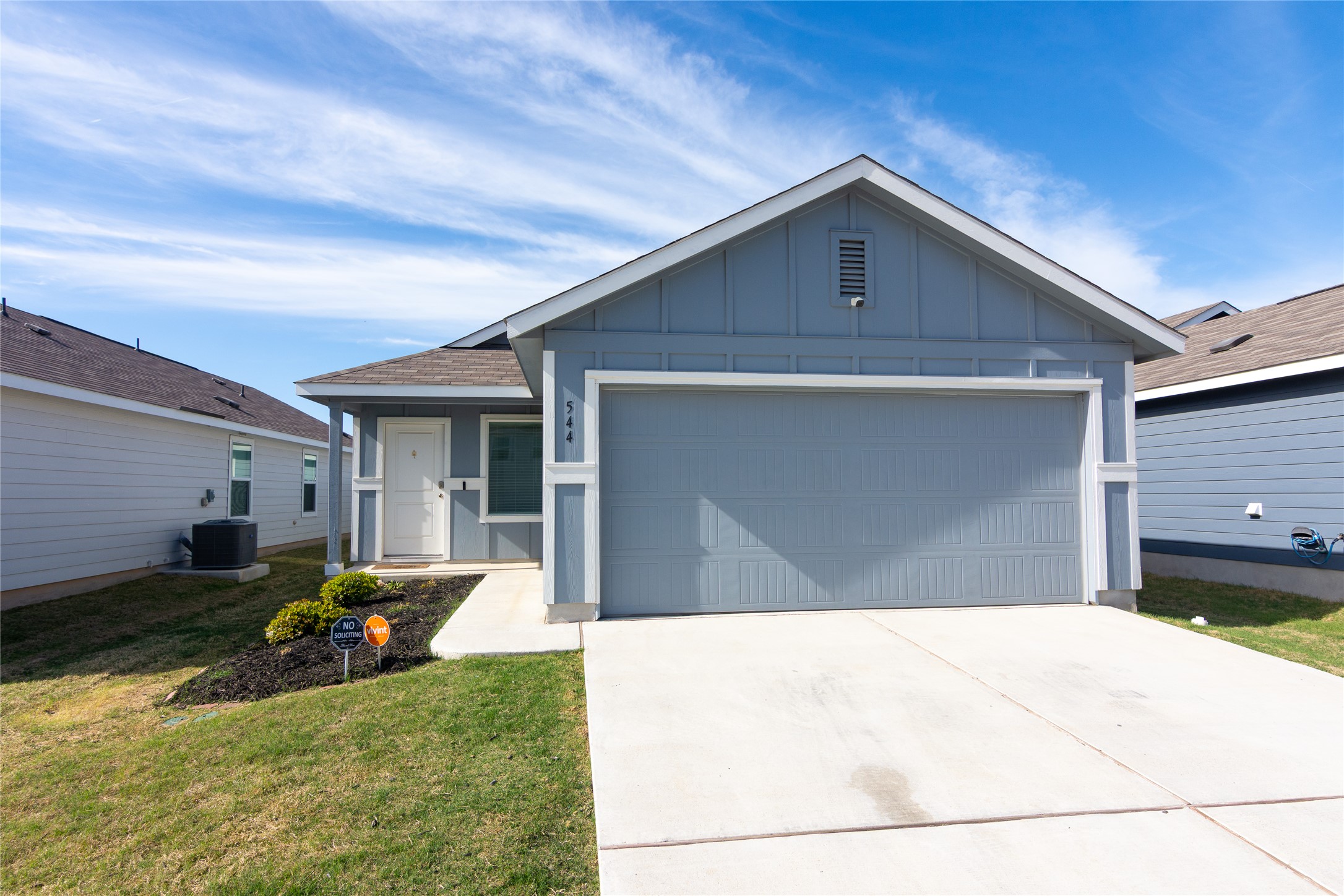 544 Rancho Del Cielo Loop Jarrell, TX 76537 - Photo 39 of 39 Ranch-style house featuring board and batten siding, a garage, driveway, a front lawn, and a shingled roof