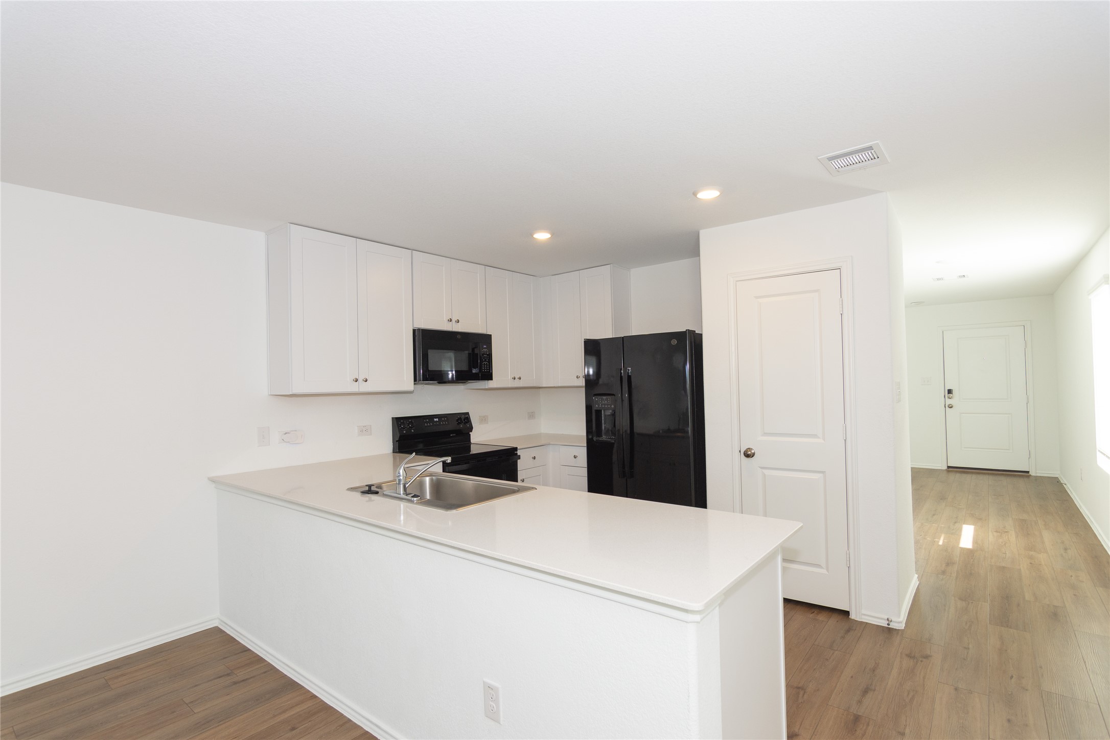 544 Rancho Del Cielo Loop Jarrell, TX 76537 - Photo 4 of 39 Kitchen featuring black appliances, light countertops, a peninsula, white cabinetry, and light wood-type flooring