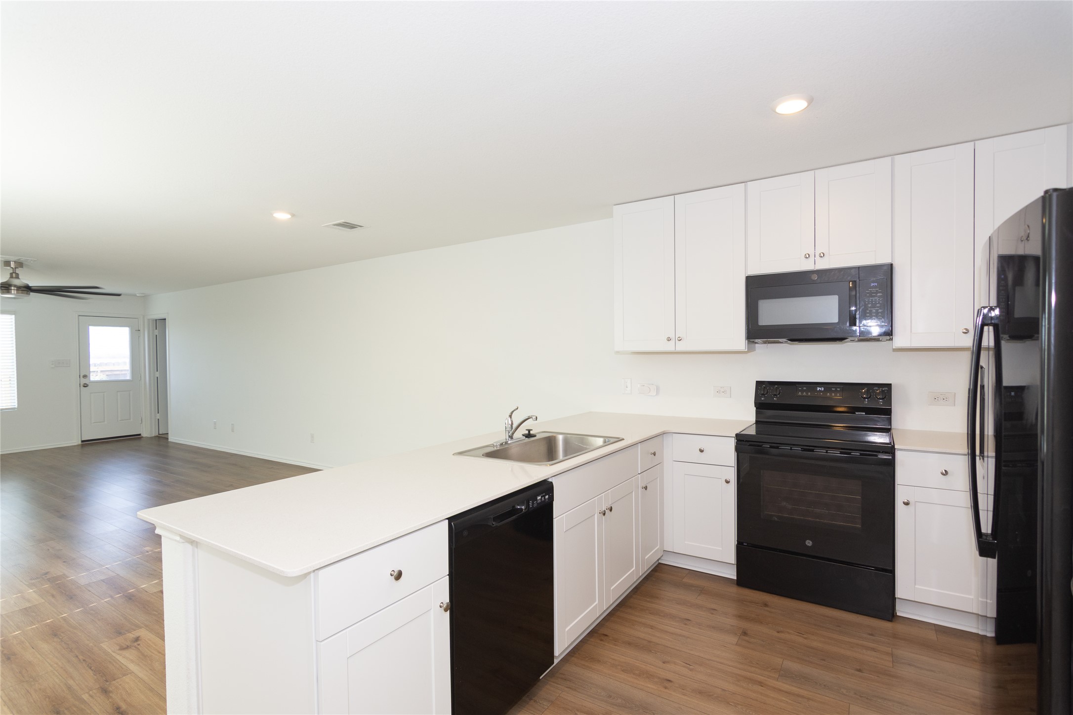 544 Rancho Del Cielo Loop Jarrell, TX 76537 - Photo 5 of 39 Kitchen with black appliances, light countertops, a peninsula, white cabinets, and recessed lighting