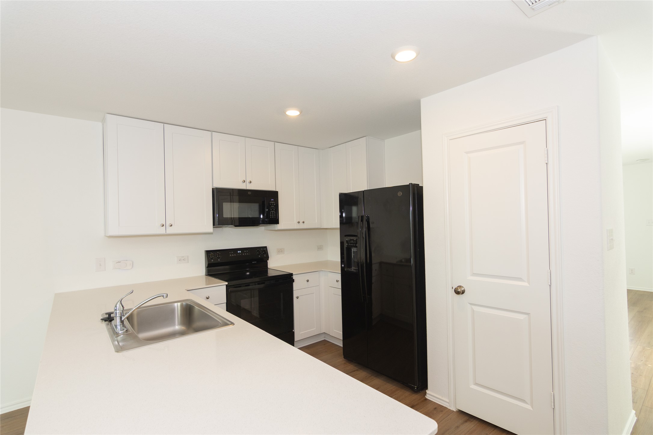 544 Rancho Del Cielo Loop Jarrell, TX 76537 - Photo 6 of 39 Kitchen featuring black appliances, light wood-type flooring, white cabinetry, light countertops, and a peninsula