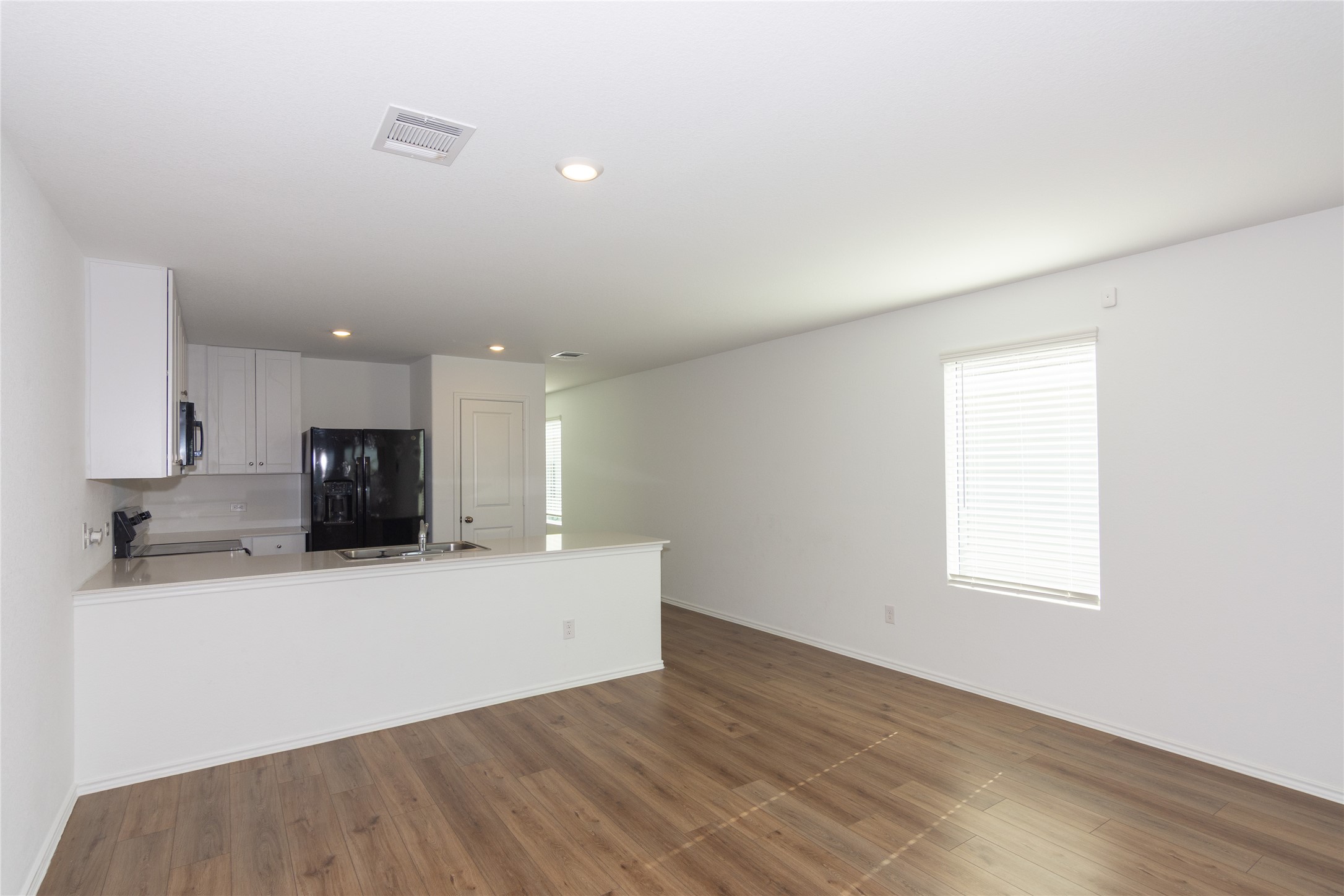 544 Rancho Del Cielo Loop Jarrell, TX 76537 - Photo 9 of 39 Kitchen with black appliances, white cabinetry, recessed lighting, a peninsula, and dark wood-style floors