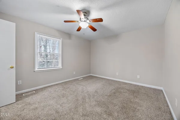an empty room with ceiling fan and window