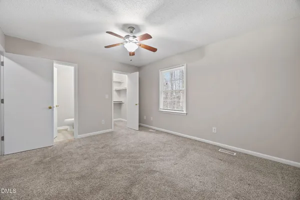 an empty room with windows and fan