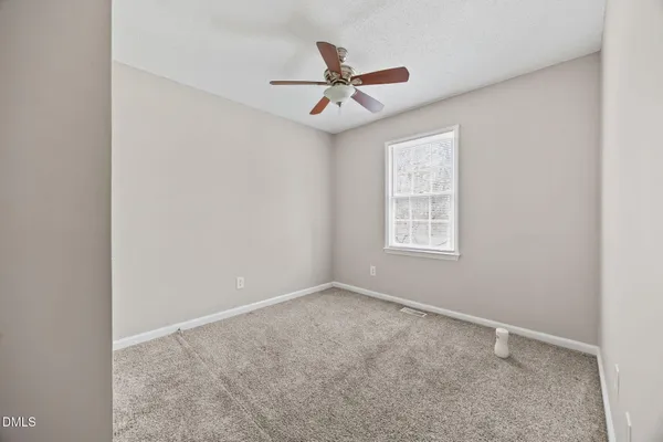an empty room with ceiling fan and window