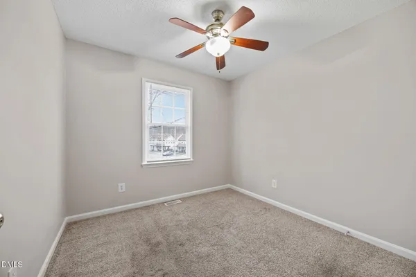 an empty room with a window and a fan