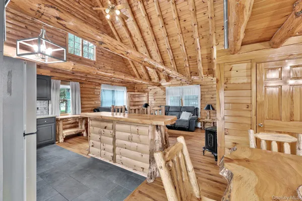 a view of living room kitchen with stainless steel appliances wooden floor and table chair