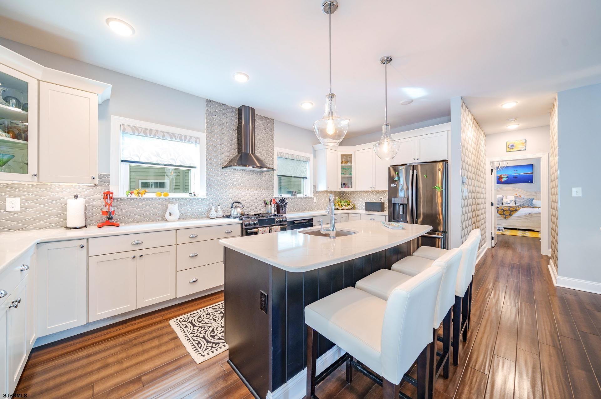 230 West Seaspray Road Ocean City, NJ 08226 - Photo 7 of 45 a kitchen with stainless steel appliances kitchen island granite countertop a sink a stove a refrigerator and island with wooden floor