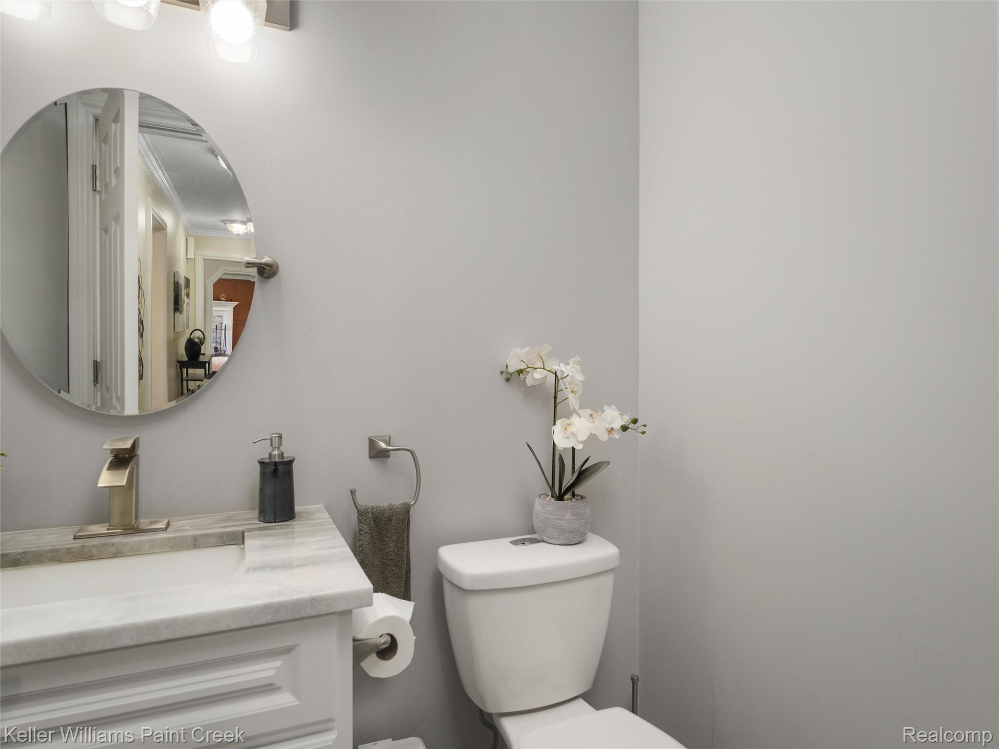 5813 36 Mile Road Romeo, MI 48065 - Photo 28 of 81 Modern bathroom featuring a circular mirror, brushed nickel fixtures, a single vanity with a stone countertop, and a white toilet