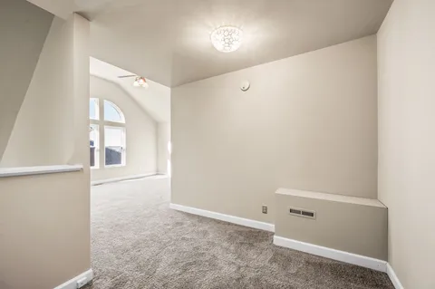 a view of an empty room with a chandelier fan