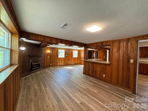en empty room with wooden floor fireplace and windows