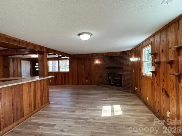 a view of a hallway with wooden floor fireplace and windows