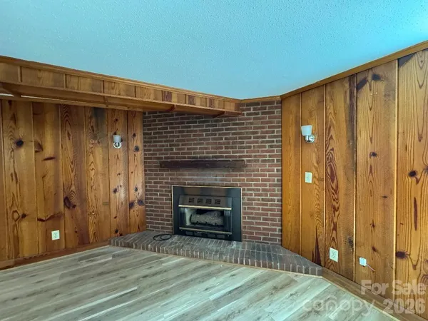 a view of an empty room with wooden floor and a fireplace