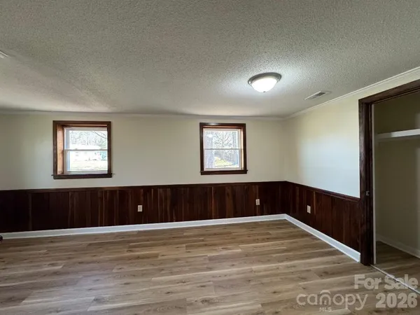 a view of an empty room with wooden floor and window