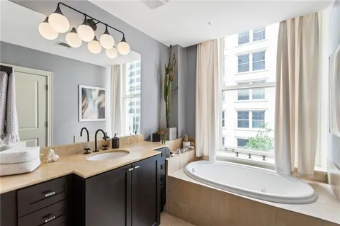 a bathroom with a double vanity sink bathtub and next to a window