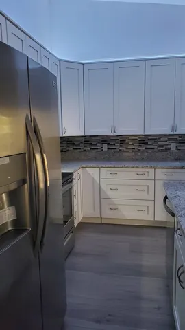 a kitchen with stainless steel appliances granite countertop a refrigerator a stove and white cabinets