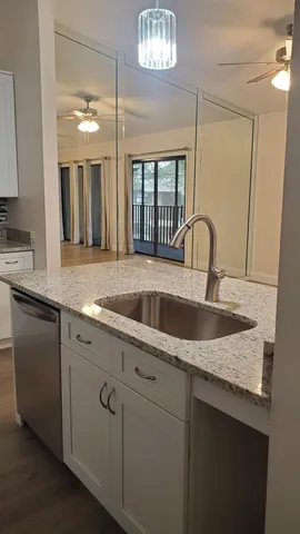 a kitchen with granite countertop a sink cabinets and wooden floor