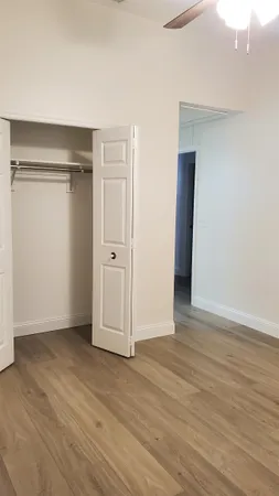 a view of an empty room with wooden floor and closet