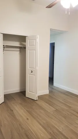 a view of an empty room with wooden floor and closet