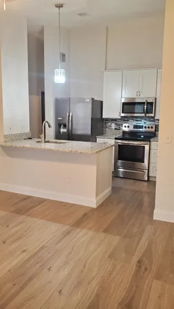 a kitchen with stainless steel appliances a stove a sink and white cabinets