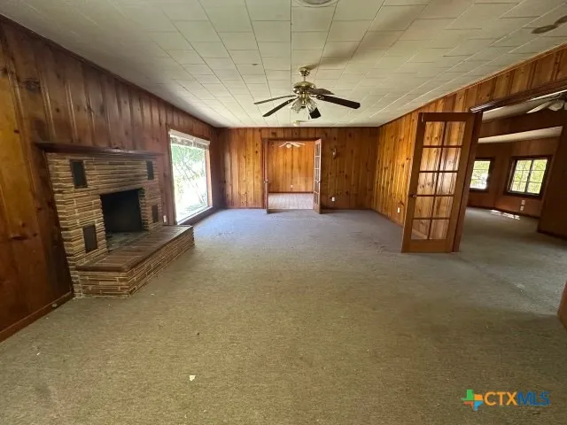 an empty room with windows fireplace and fan