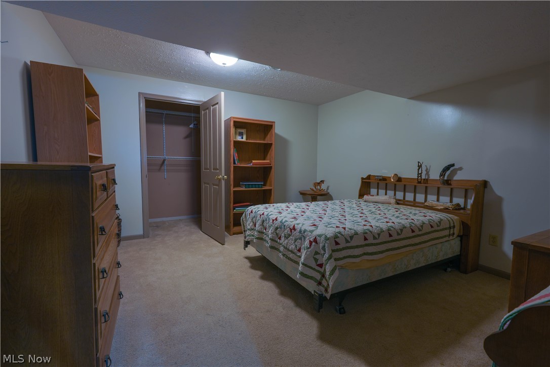 5675 Post Boy Road Southwest Newcomerstown, OH 43832 - Photo 19 of 26 Carpeted bedroom featuring a walk in closet, a closet, and a textured ceiling