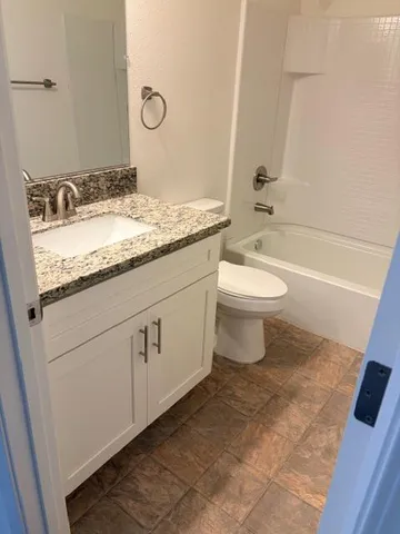 a bathroom with a granite countertop sink toilet and shower