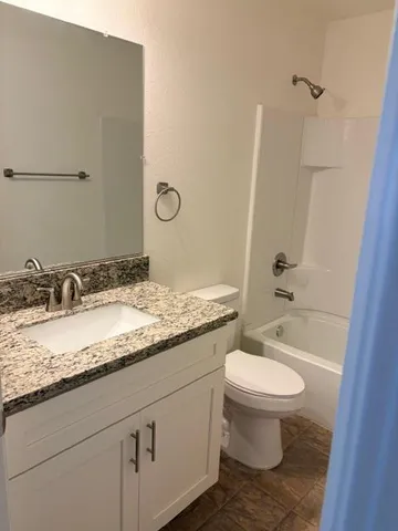 a bathroom with a granite countertop sink a toilet and a mirror
