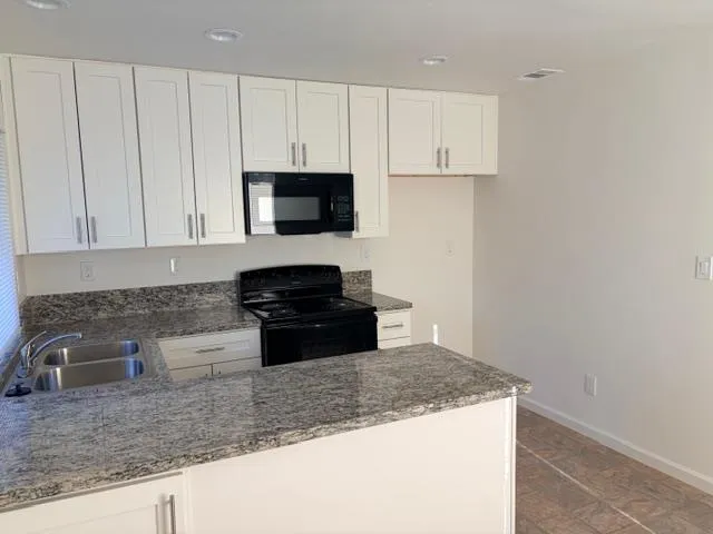 a kitchen with granite countertop a sink a stove and microwave