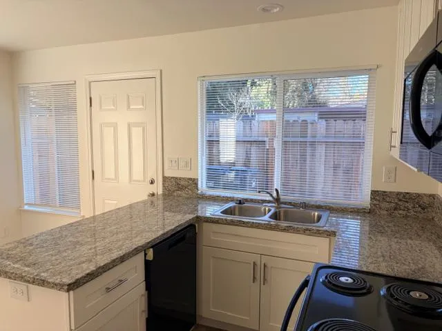 a kitchen with granite countertop a sink a stove and cabinets