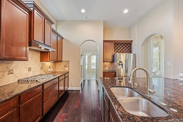 a kitchen with granite countertop a sink a stove and cabinets