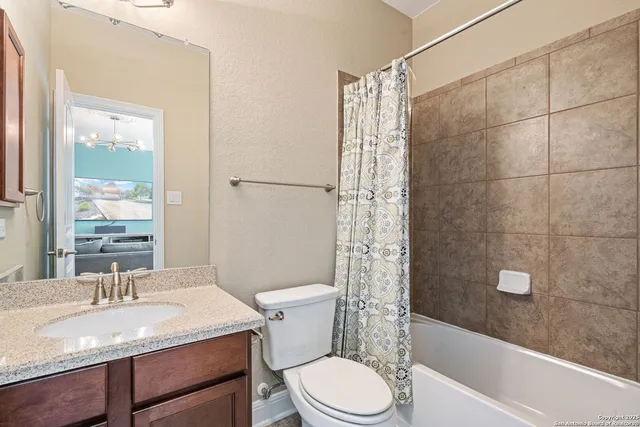 a bathroom with a granite countertop sink a toilet a mirror and shower