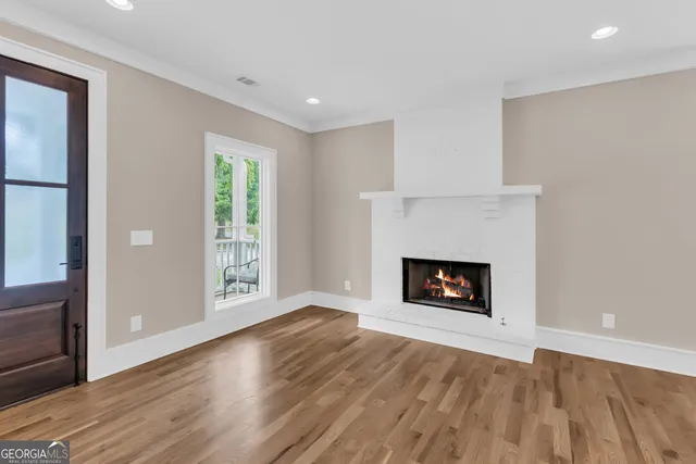 an empty room with wooden floor fireplace and windows