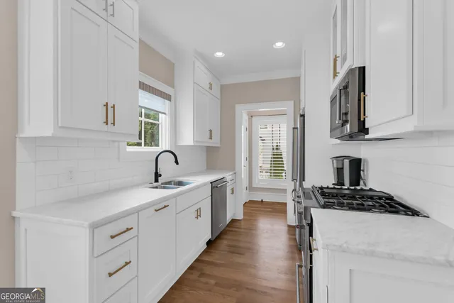 a kitchen with white cabinets stainless steel appliances and a sink