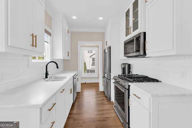 a kitchen with stainless steel appliances granite countertop a stove top oven a sink a refrigerator and white cabinets