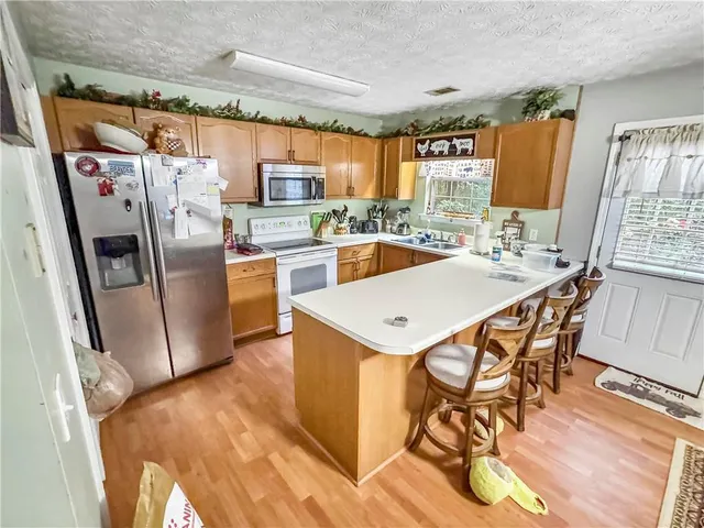 a kitchen with stainless steel appliances a stove a refrigerator a sink dishwasher and a dining table with wooden floor