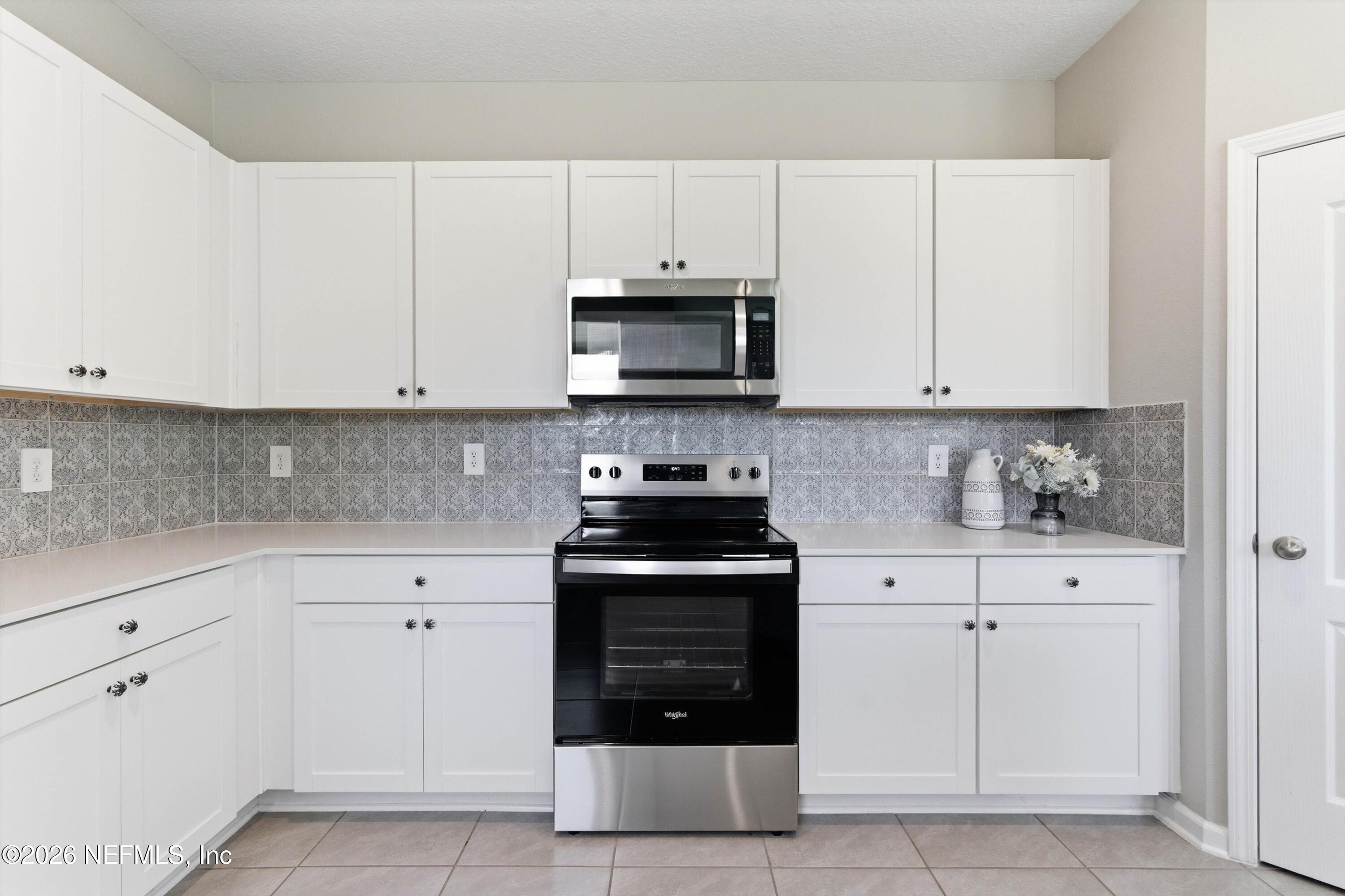 103 Seaport Breeze Road St. Augustine, FL 32095 - Photo 9 of 44 a kitchen with white cabinets and black appliances