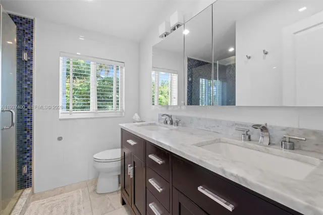 a bathroom with a granite countertop sink a toilet a mirror and a window