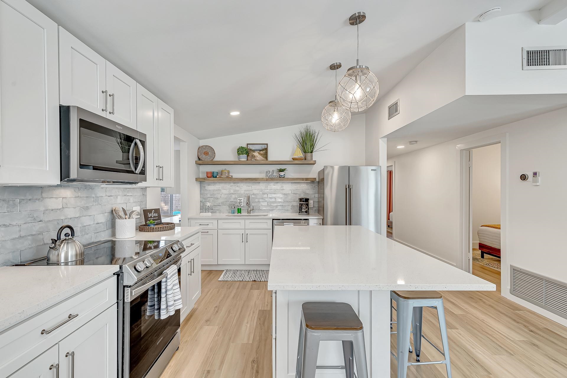 110 Terrapin Road St. Augustine, FL 32086 - Photo 5 of 46 a large kitchen with stainless steel appliances granite countertop a stove refrigerator a microwave oven a sink dishwasher and white cabinets with wooden floor