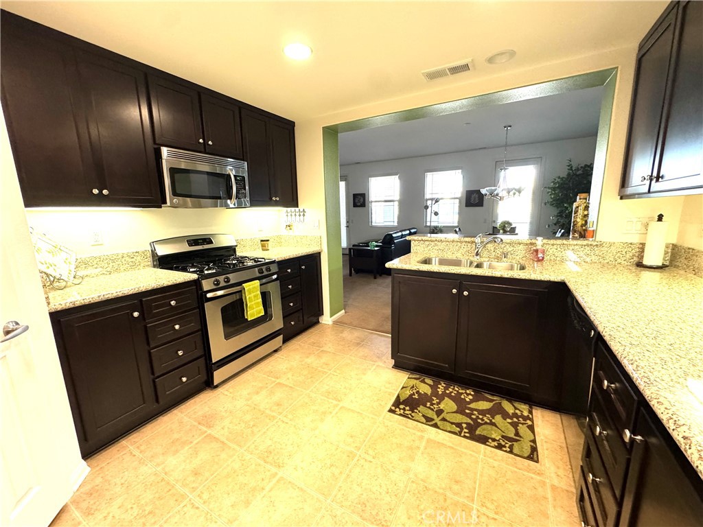 7666 Papyrus Place, Unit 2 Rancho Cucamonga, CA 91739 - Photo 22 of 23 a kitchen with stainless steel appliances granite countertop wooden cabinets a stove top oven a sink and dishwasher