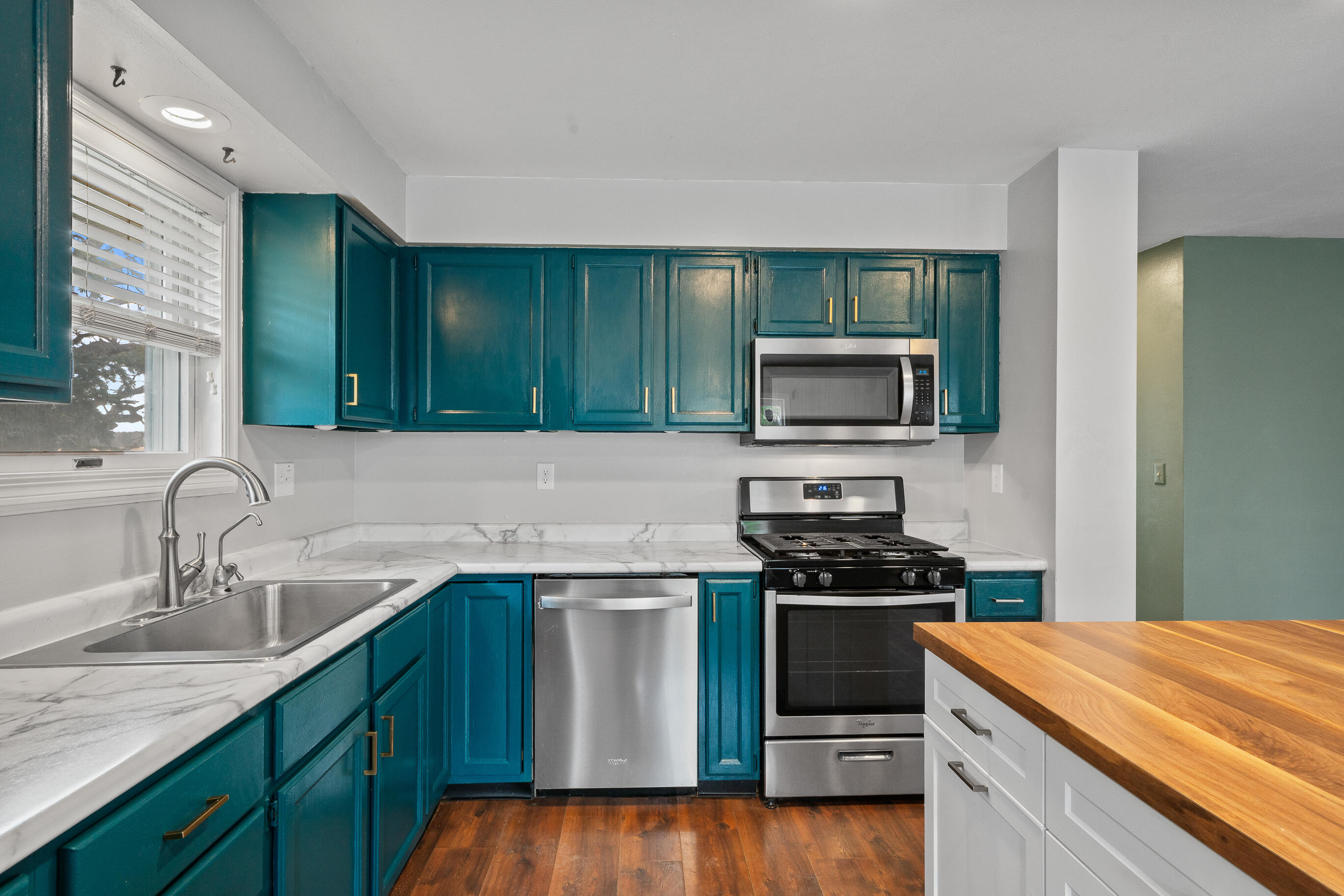 2212 Borg Road Delavan, WI 53115 - Photo 13 of 43 Kitchen with teal cabinets, gold hardware, marble-look countertops, stainless steel dishwasher, gas range, over-the-range microwave, and butcher block styled island